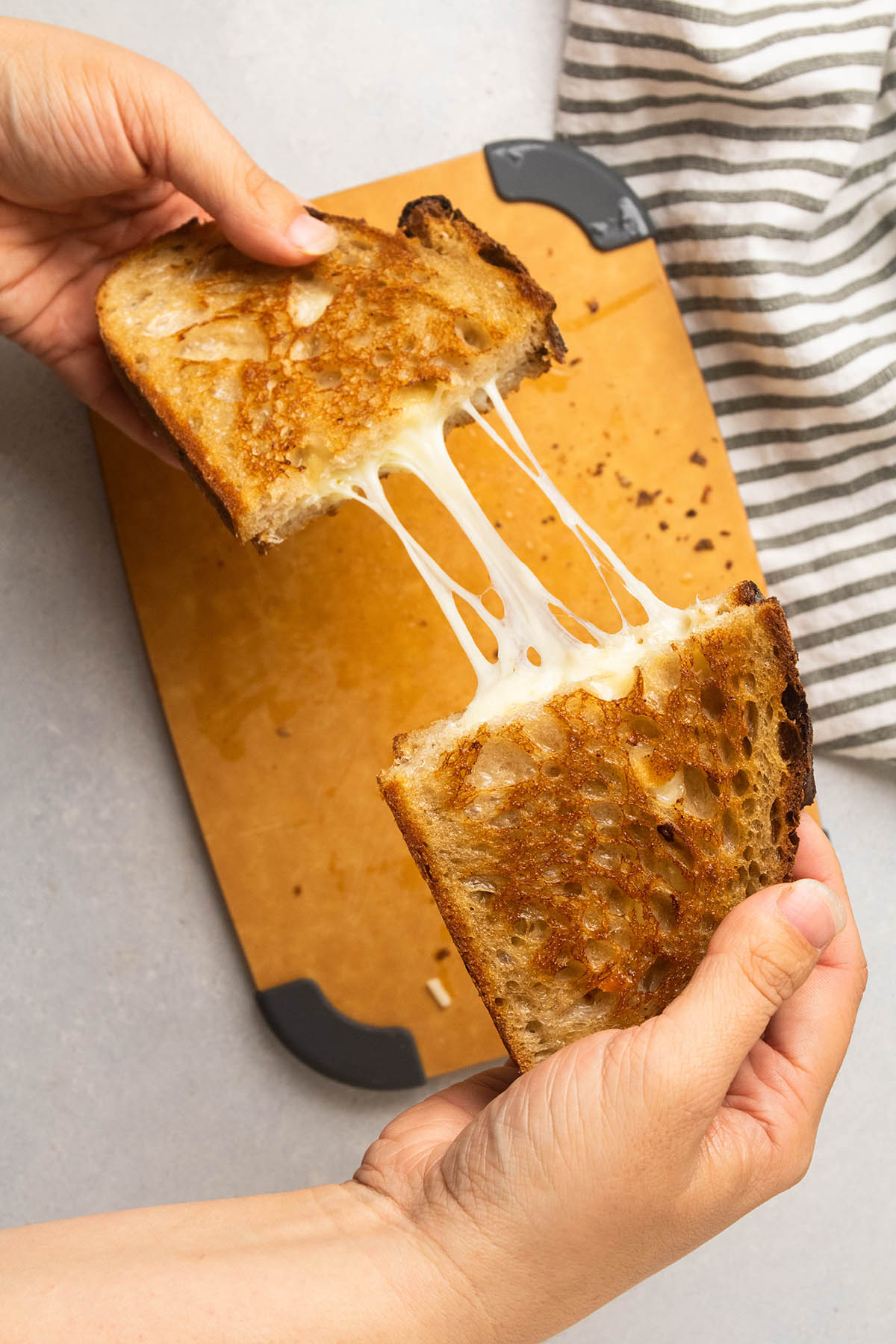 Pulling sandwich apart as cheese stretches.